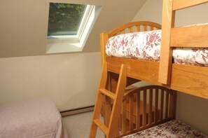 A bunk bed with a wooden ladder, a window with a view of greenery, and a small bedside table with a floral-patterned pillow. - Sugarloaf Mountain Snowbrook Village C2674 (Carrabassett Vly)