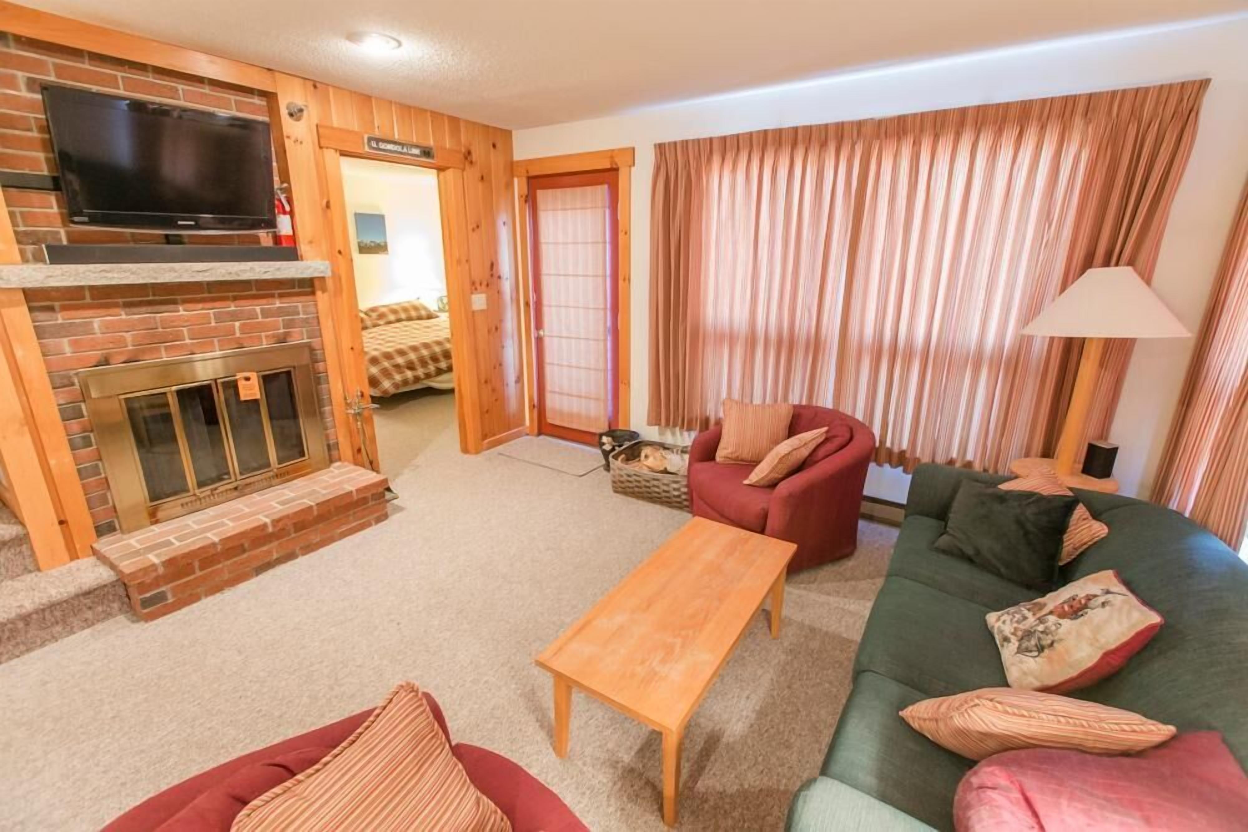 A cozy living room with a fireplace, a television, and a sofa.