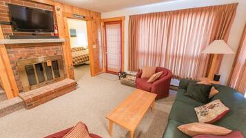 A cozy living room with a fireplace, a television, and a sofa.