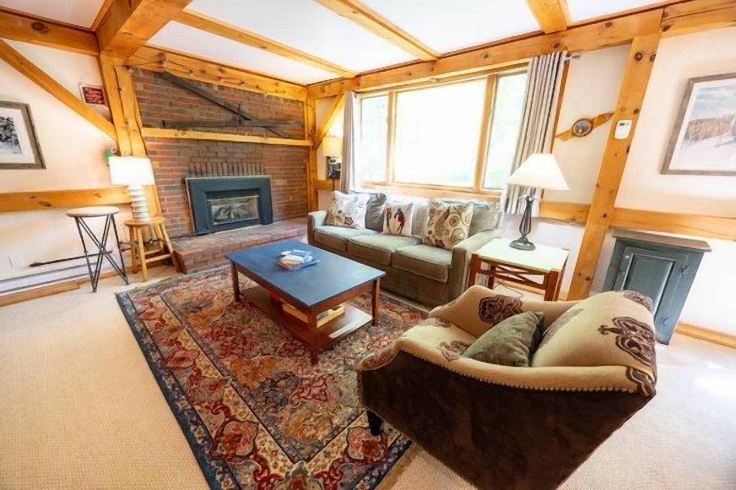 A cozy living room with a fireplace, a sofa, a coffee table, and a rug.