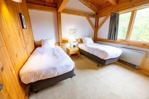 Une chambre avec deux lits, des murs en bois, une fenêtre et un radiateur.