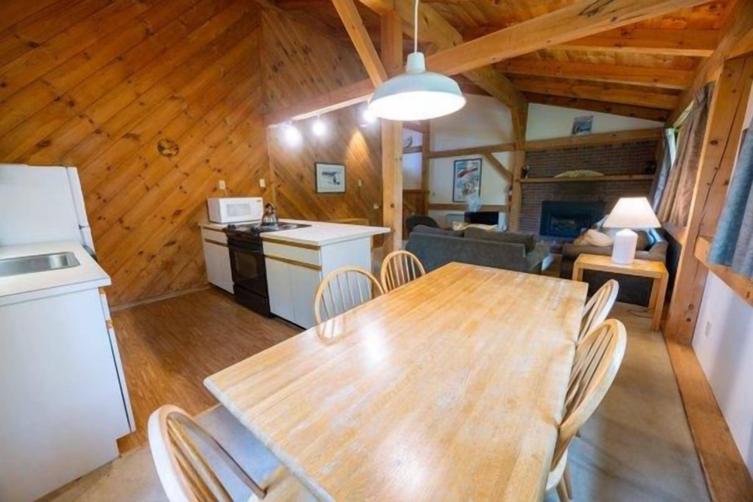 Una cocina compacta con una mesa y sillas de madera, un microondas y un fregadero.