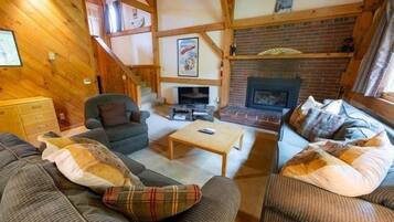 Una sala de estar acogedora con chimenea, vigas de madera y una escalera.