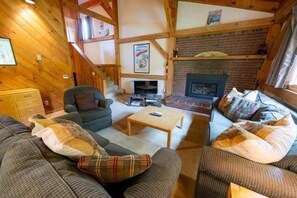 Ein gemütliches Wohnzimmer mit Kamin, Holzbalken und einer Treppe.