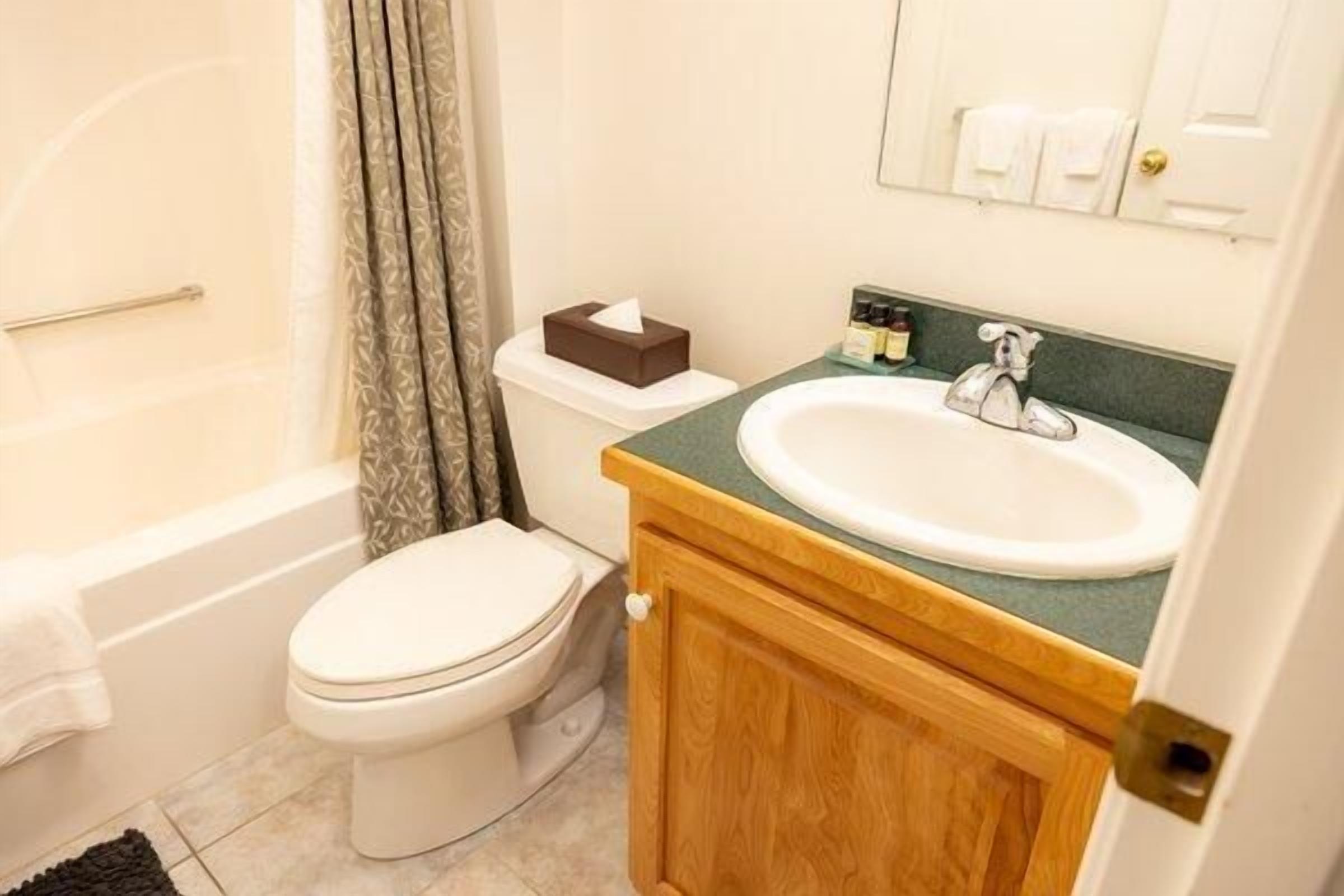 A bathroom with a bathtub, toilet, sink, and wooden cabinet.