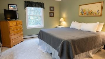 A bedroom with a bed, dresser, window, and artwork.