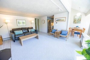 Ein Wohnzimmer mit einer Couch, einem Couchtisch und einem Essbereich mit Stühlen und einem Tisch.