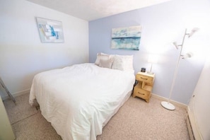A bedroom with a bed, a nightstand, a lamp, and a painting on the wall. - Sugarloaf Mountain Kibby Mountain Road C2318 (Carrabassett Vly)