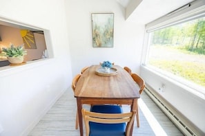 A dining area with a wooden table and blue chairs, a potted plant, and a window with a view of greenery. - Sugarloaf Mountain Kibby Mountain Road C2318 (Carrabassett Vly)