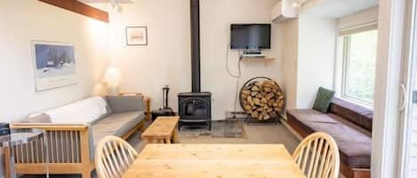 Una habitación acogedora con una mesa de comedor de madera, sillas, un sofá, un televisor y una chimenea.