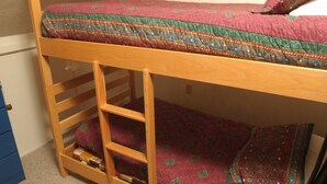 Un letto a castello con struttura in legno, un materasso a motivi rossi e verdi e un cuscino.