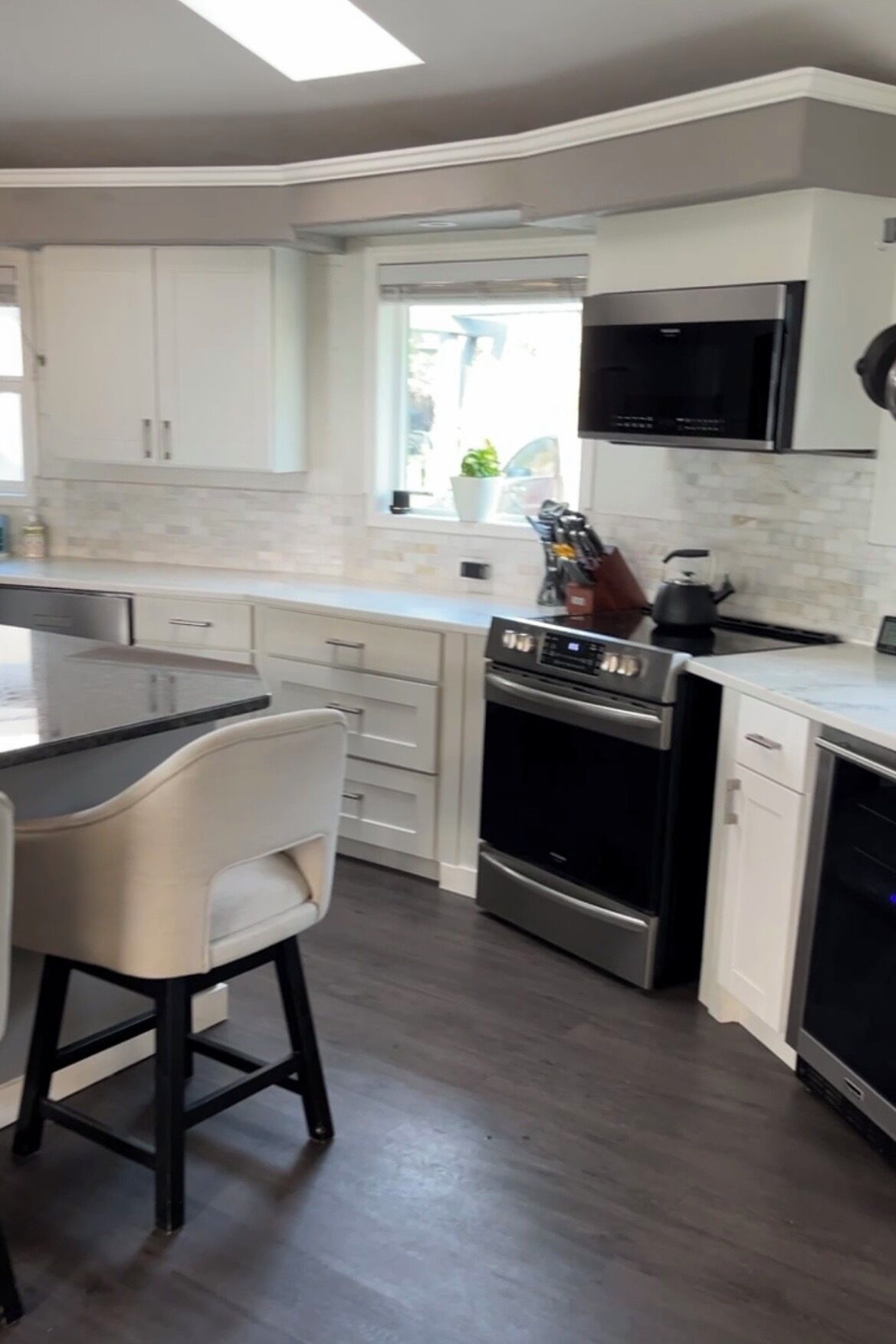 A modern kitchen with white cabinetry, a stainless steel range, and a built-in oven.