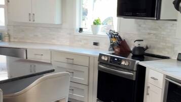 A modern kitchen with white cabinetry, a stainless steel range, and a built-in oven.