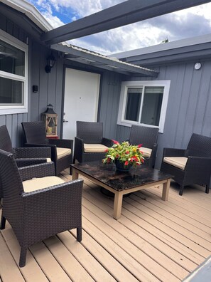 A covered patio with wicker furniture and a table, a potted plant, and a lantern.