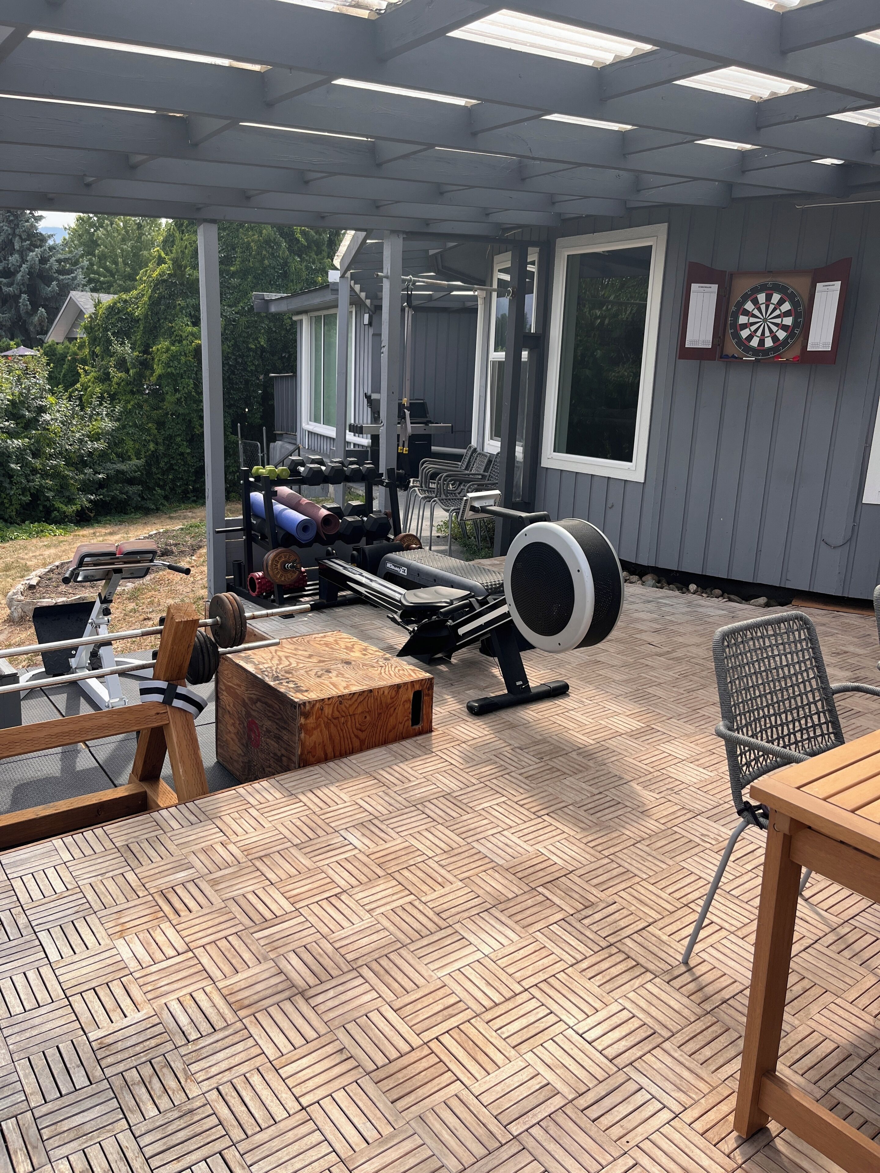 An outdoor patio with exercise equipment, a table, and chairs.