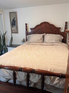 A bed with a wooden headboard, a nightstand with a lamp, and a poster on the wall.