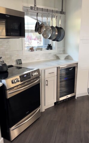 A modern kitchen with stainless steel appliances, a microwave, and hanging pots.