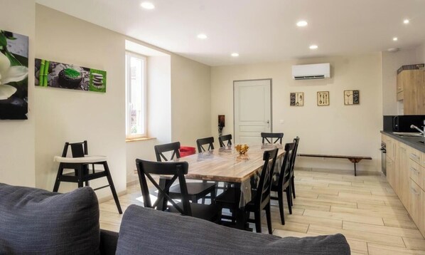 A dining area with a wooden table and chairs, a kitchen with cabinets, and a door. - Community Guesthouse - ESCANECRABE (ESCANECRABE)