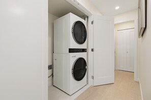 Una lavanderia con due lavatrici affiancate e una porta che dà su un'altra stanza.