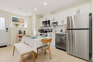Una cucina moderna con mobili bianchi, elettrodomestici in acciaio inossidabile e un'area pranzo con un tavolo apparecchiato per due persone.