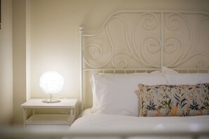 Un letto rifatto con un cuscino a fiori e una testiera bianca.
