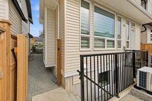 A residential building with a gated entrance, a wooden fence, and a gravel driveway. - Luxurious 2BR Suite Near Langley Events Centre | King Bed | Fully Equipped (Langley Township)