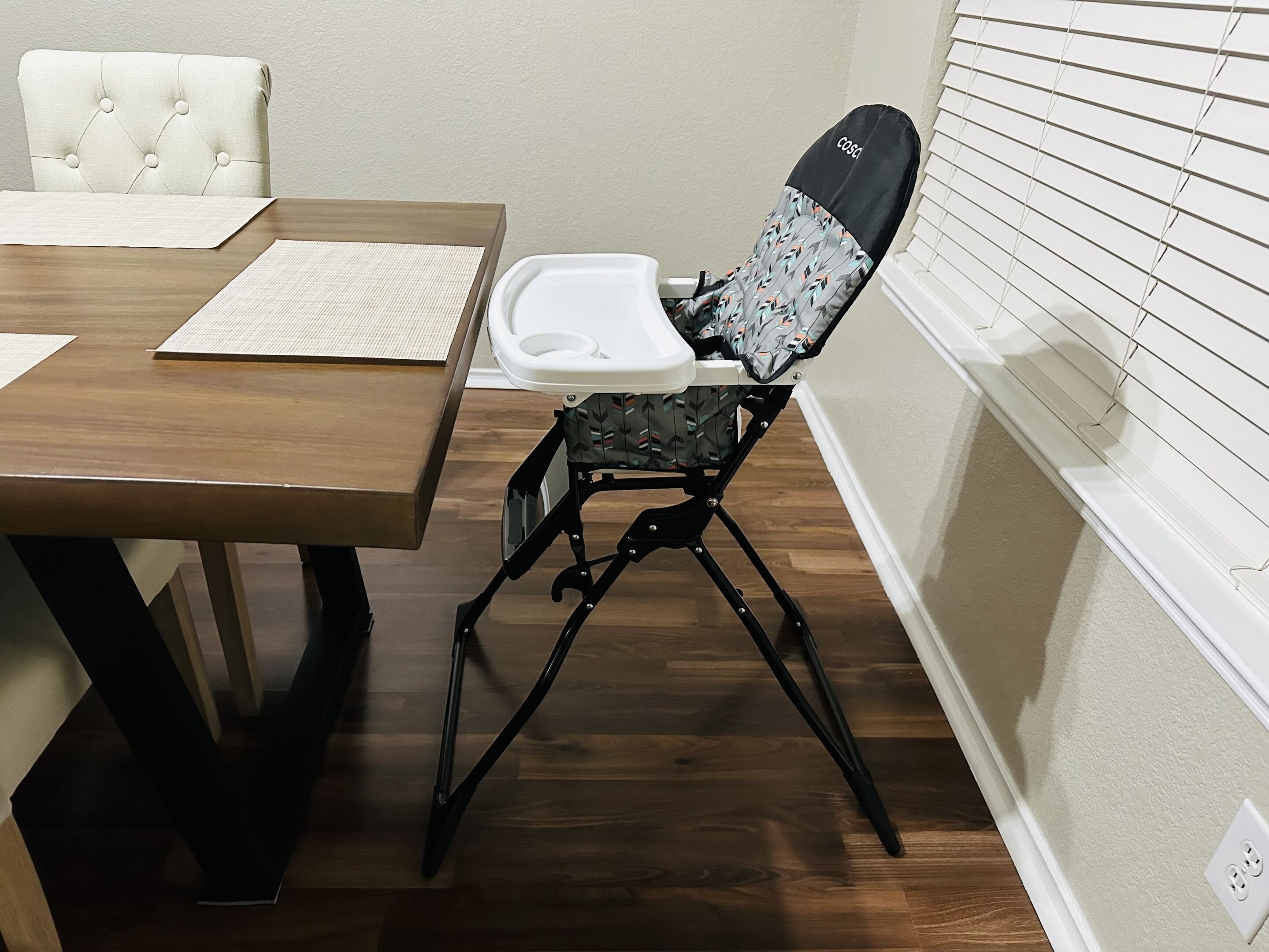 Un coin repas comprenant une table en bois, une chaise rembourrée et une chaise blanche.