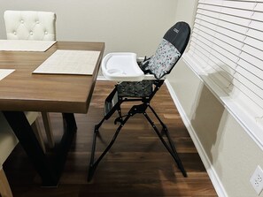 A dining area with a wooden table, a cushioned chair, and a white chair.