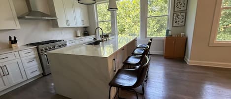 A spacious kitchen with a large island, white cabinetry, and a bar stool seating area.
