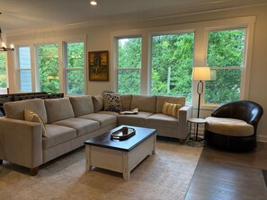 A living room with a sectional sofa, a coffee table, a lamp, and a foosball table.