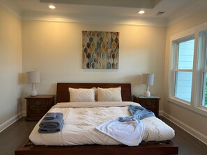 A bedroom with a bed, two nightstands, a window, and a wall art piece.
