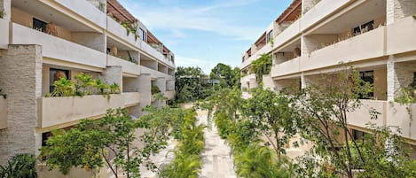 Un hôtel à plusieurs étages doté d’une cour intérieure bordée d’une végétation luxuriante et surplombant un ciel dégagé.