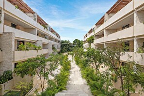 A multi-story hotel with a central courtyard surrounded by lush greenery and a clear sky. - Tulum 2BR Private Plunge Pool 2 King Beds (Tulum)