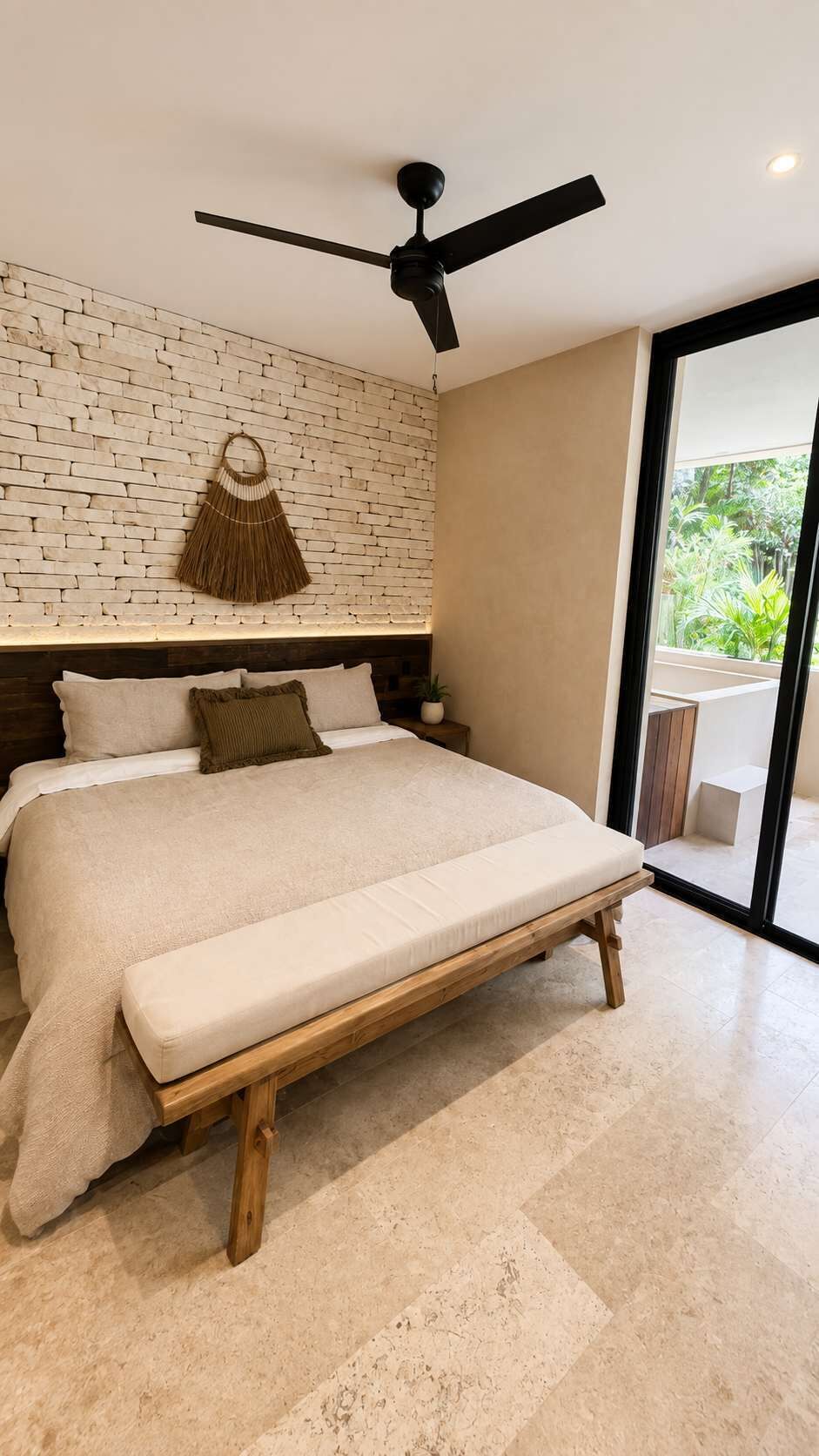 Une chambre moderne avec un grand lit, un ventilateur de plafond, un mur en briques et une vue sur la verdure.