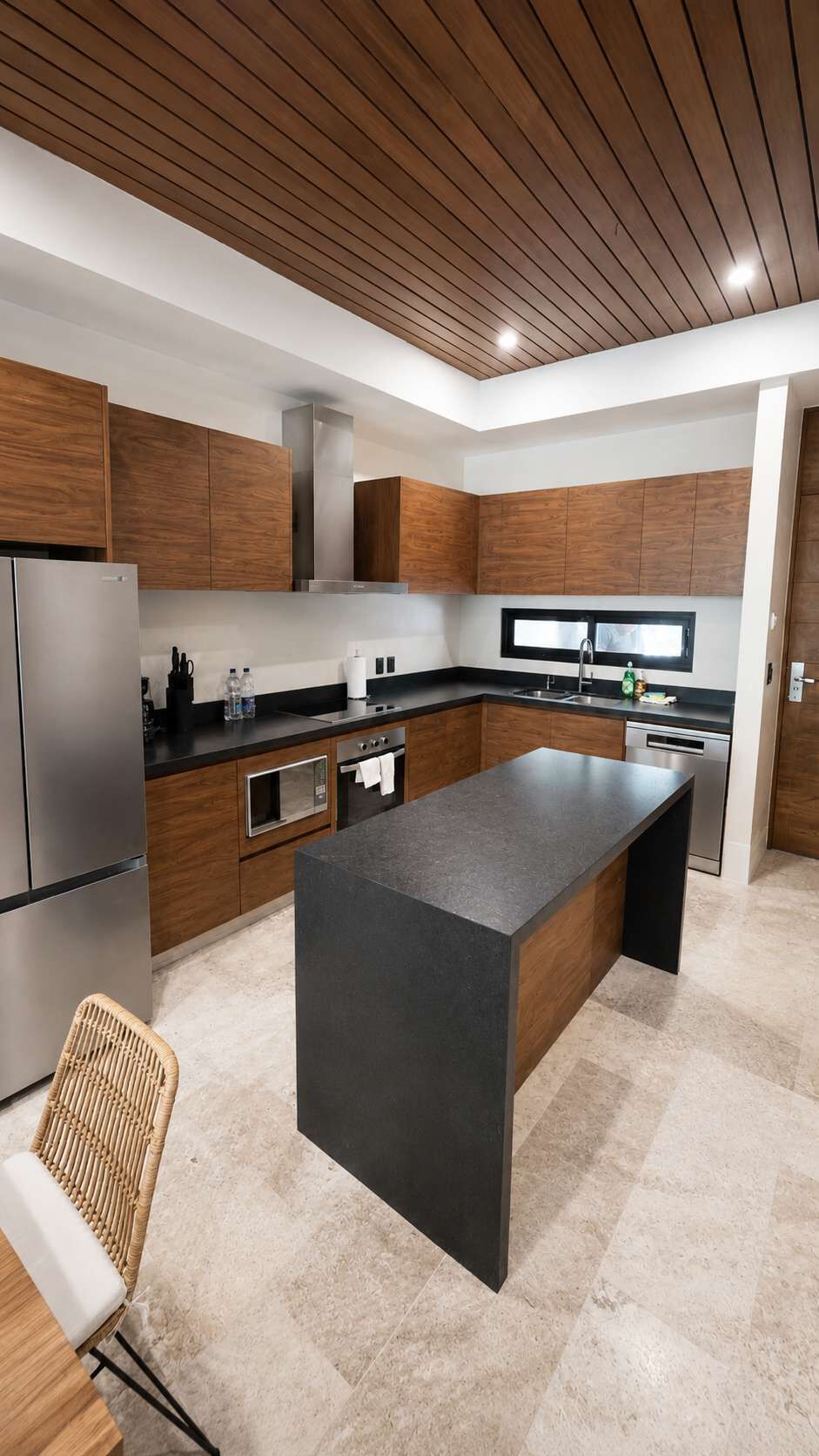 Eine moderne Küche mit Holzschränken, einer großen Kochinsel, Edelstahlgeräten und Fliesenboden.