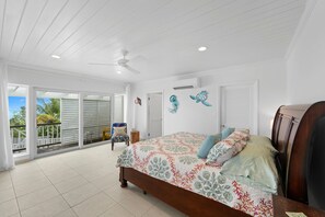 Ein Schlafzimmer mit Bett, Deckenventilator und Blick ins Freie.