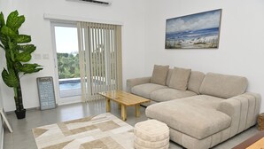 Ein Wohnzimmer mit einer Couch, einem Couchtisch, einem Teppich, einer Topfpflanze und einem Bild an der Wand.