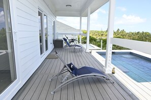 A covered outdoor area with a pool, lounge chairs, and a view of the surrounding landscape. - Brand New Beach Villa with Pool, Walk to La Bougainvillea Restaurant and Bar (Governor's Harbour)
