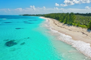 A beach with clear turquoise waters and a sandy shore. - Brand New Beach Cottage with Pool, Walk to La Bougainvillea Restaurant and Bar (Governor's Harbour)