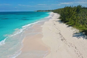 A beach with clear turquoise waters and a sandy shore. - Brand New Beach Cottage with Pool, Walk to La Bougainvillea Restaurant and Bar (Governor's Harbour)