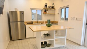 Una cocina moderna con un refrigerador de acero inoxidable, una encimera de madera y un lavamanos integrado.