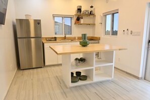 Eine moderne Küche mit einem Edelstahl-Kühlschrank, einer Holz-Arbeitsplatte und einer integrierten Spüle.