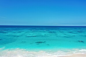 Ein klarer Blick auf einen Strand mit türkisblauem Wasser und weißem Sand.