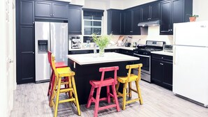 A modern kitchen with black cabinets, stainless steel appliances, and a central island with two chairs.