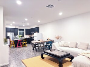 A modern living room with a sofa, coffee table, and a dining area with chairs and a table.