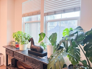 A room with a wooden desk, a potted plant, a decorative horse sculpture, and a window with blinds.