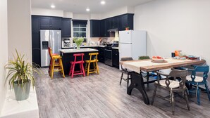 A modern kitchen with dark cabinetry, a central island with stools, and a dining table with chairs.