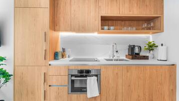 A modern kitchen with wooden cabinets, a Bosch oven, a coffee maker, and a sink.