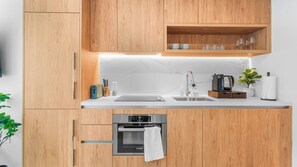 A modern kitchen with wooden cabinets, a Bosch oven, a coffee maker, and a sink. - The Crosby Miami Condos (Miami)