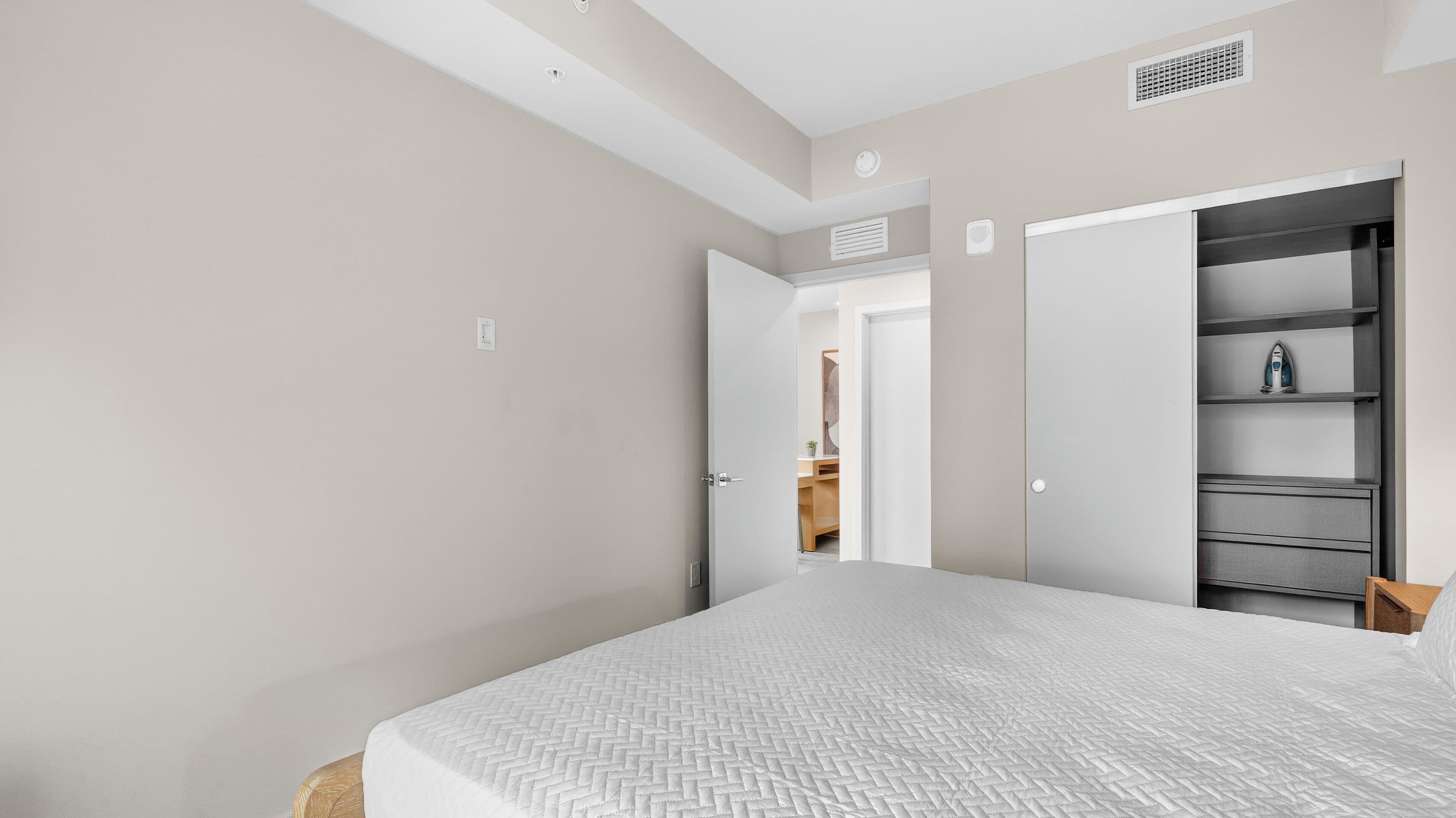 A bedroom with a bed, a wardrobe, and a door leading to a bathroom.